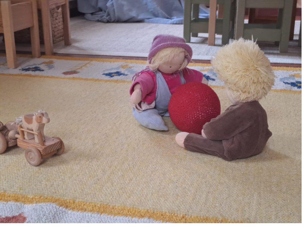 Waldorf-Spielzeug – Puppen und Holzfahrzeug auf dem Teppich
